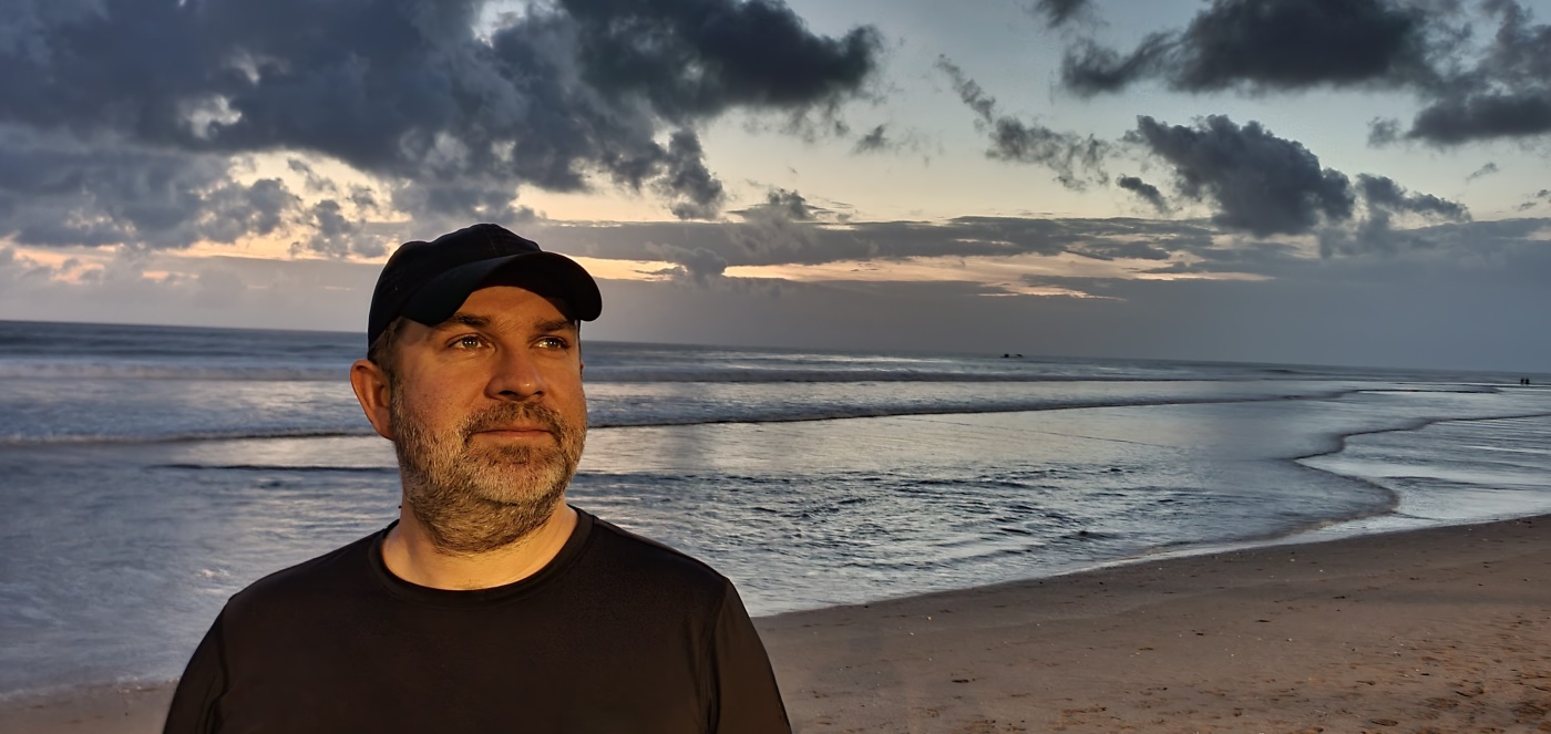 Portret plaża Seminyak edited Mężczyzna w lnianej koszuli uśmiecha się na pokładzie jachtu na Langkawi, w tle turkusowe morze i wysepki